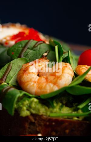 Buckwheat bread toasts with a poached egg, a sliced avocado, a shrimps, tomatoes and lettuce. Dietary menu. Flat lay Stock Photo