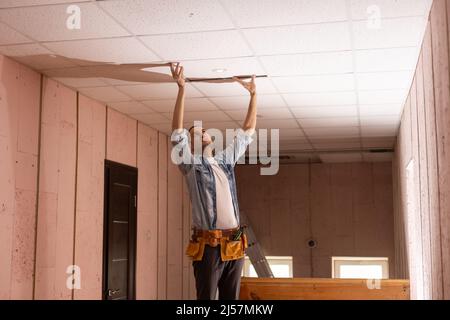 An electrician fixing wires, installing light on the ceiling Stock Photo