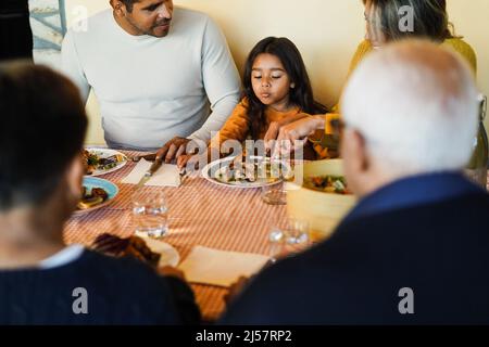 Happy latin family having fun eating together home - Focus on girl face Stock Photo