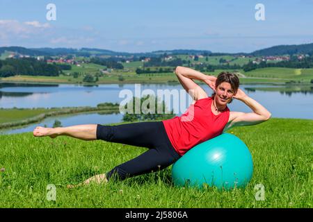 Pilates excercises on a meadow in summer Stock Photo
