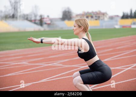 side view of sportswoman doing sit ups with outstretched hands Stock Photo
