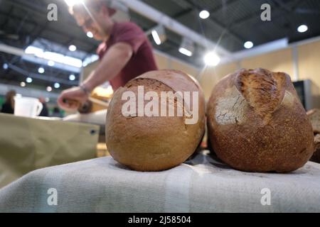 Leipzig, Germany. 21st Apr, 2022. A baker shows his skills at the Agra 2022 fair, while in the foreground are loaves of bread. The trade show Agra 2022 takes place from 21.04. to 24.04.2022. Credit: Sebastian Willnow/dpa/Alamy Live News Stock Photo