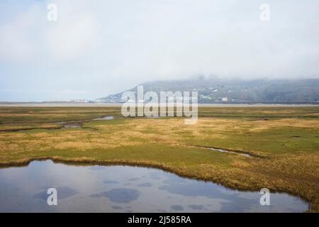 A low mist hangs over Barmouth viewed from the salt marshes across the estuary Stock Photo