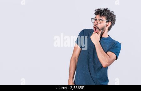 Amazed young man with hand near open mouth, man looking aside with face scared expression, surprised guy on isolated background Stock Photo