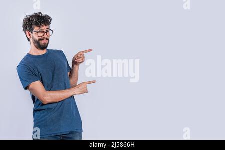 Handsome man pointing to the side, friendly guy pointing his fingers to the side, young man pointing at blank space Stock Photo