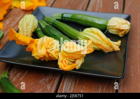Southern German cuisine, fresh courgette flowers with courgette (Cucurbita pepo var. giromontiina) on plate, vegetarian, healthy cuisine, cooking Stock Photo