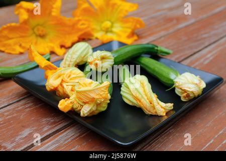Southern German cuisine, fresh courgette flowers with courgette (Cucurbita pepo var. giromontiina) on plate, vegetarian, healthy cuisine, cooking Stock Photo