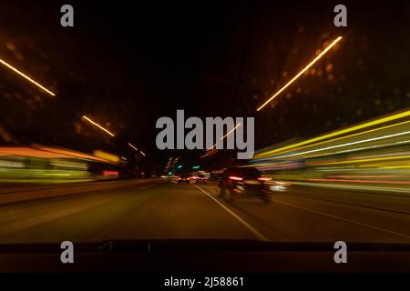 When driving fast, pulling lights from the car and buildings when looking through the windscreen on a night tour Stock Photo