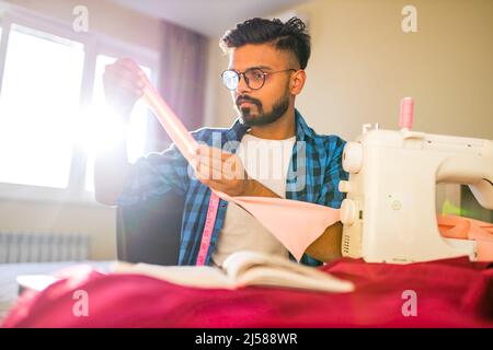indian man sewing new collection in showroom in living room Stock Photo