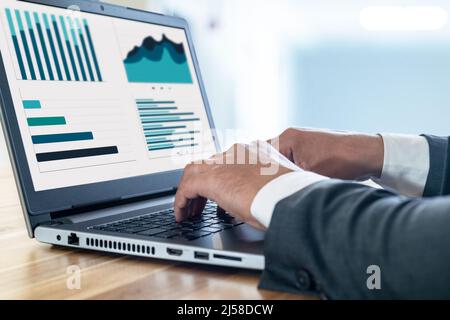 Close up photo of businessman using laptop and computer. Concept of data chart statistics and income and revenue infographics with screen mockup. Stock Photo