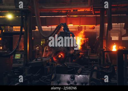 Metal casting in metallurgical plant or factory. Process of melting and forming production of iron pipes in industrial machines in workshop. Stock Photo