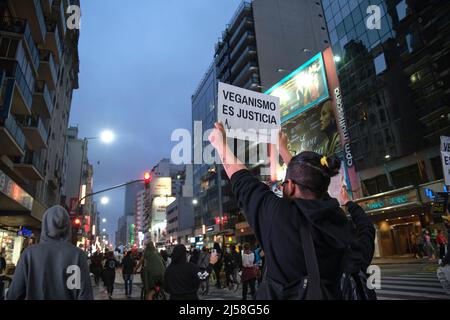 Buenos Aires, Argentina; Nov 1, 2021: World Vegan Day. Activists marching down Corrientes Street at dusk. Man holding a poster: Veganism is justice. Stock Photo