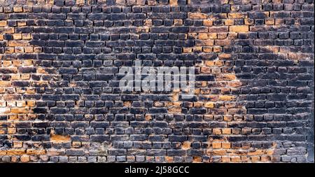 Close up photo of rustic and retro styled brick wall texture background. Old dark and black stained pattern design. Stock Photo