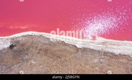 Flying over a pink salt lake. Salt production facilities saline evaporation pond fields in the salty lake. Dunaliella salina impart a red, pink water Stock Photo