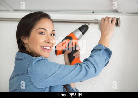 happy woman installing blinds with screwdriver Stock Photo