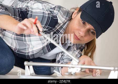 female worker is assembling metal-plastic window in workshop Stock Photo