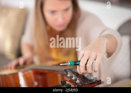 woman as trainee cleaning guitar in guitar maker workshop Stock Photo