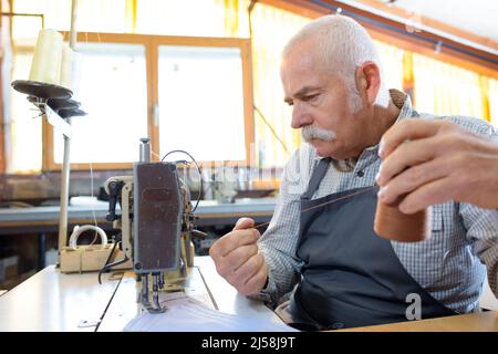 senior man using industrial sewing machine Stock Photo