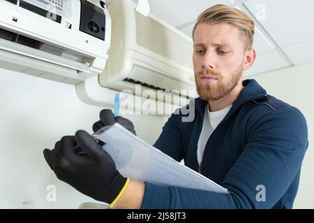 young male technician checking air conditioning system Stock Photo