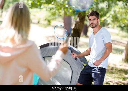 young smiling couple playing badminton outdoors Stock Photo