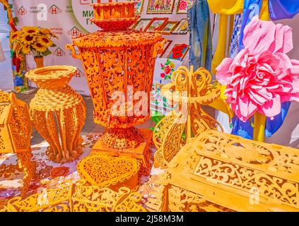 The wooden carved samovar, vase, plate and other kitchenware on the showcase of craftsmen's stall on Fair due Independence Day celebration in Dnipro, Stock Photo