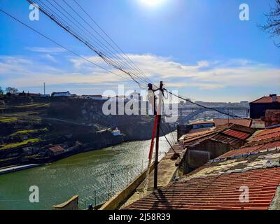 Electricity service worker fixinig wires, aerial cityscape in bright sunshine Porto, Portugal Stock Photo