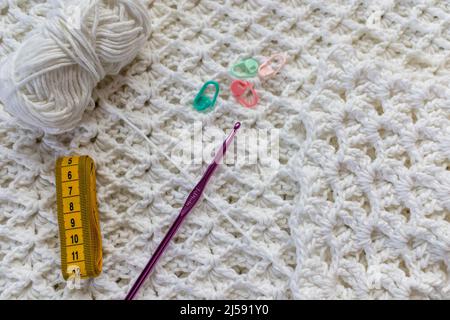 https://l450v.alamy.com/450v/2j591y0/white-cotton-blanket-with-original-embossed-crochet-stitch-pattern-ball-5-mm-purple-crochet-hook-yellow-measuring-tape-green-and-pink-markers-par-2j591y0.jpg