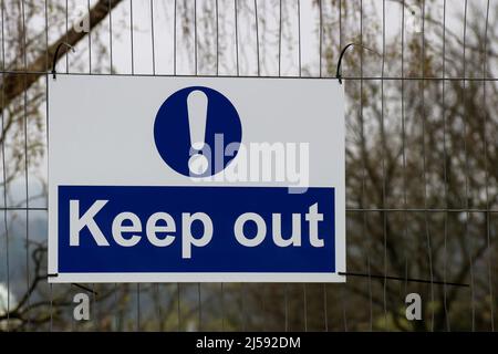 Keep out sign hanging on a building site perimeter fence Stock Photo