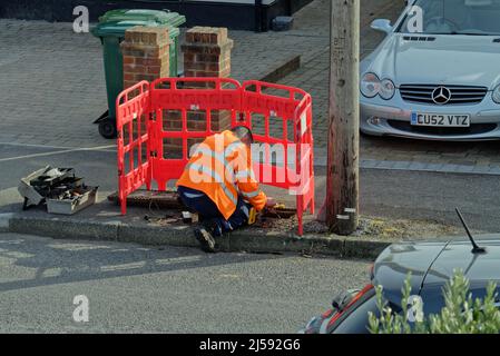 A BT Openreach communications engineer working on a  telephone line box on a suburban street Surrey England UK Stock Photo