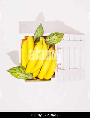 Fresh green apples with leaves in a wooden box on a white background. Healthy season fruits with lots of vitamins. Eco friendly fruits packaging and s Stock Photo