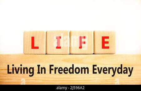 LIFE living in freedom everyday symbol. Concept words LIFE living in freedom everyday on wooden blocks on a beautiful white background. Business LIFE Stock Photo