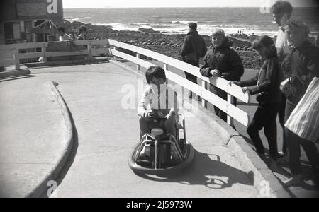 1960s, historical, at the seaside, a young girl riding on a battery powered mini go-kart at a concrete track, England, UK. Stock Photo