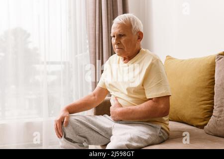 Senior man is suffering from problems with a digestion at home Stock Photo