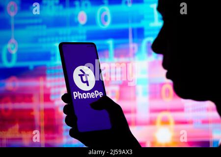 In this photo illustration, a silhouetted woman holds a smartphone with the PhonePe logo displayed on the screen. Stock Photo