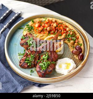 Raw rack of lamb fried with aromatic with hummus and yogurt Stock Photo