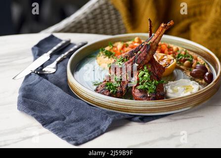 Raw rack of lamb fried with aromatic with hummus and yogurt Stock Photo