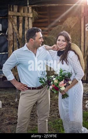 bride in cowboy style sits on threshold of hayloft Stock Photo