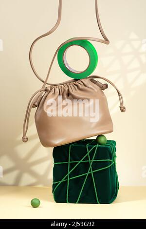 Conceptual creative modern Still life, balance composition. Beige handbag on a podium covered with green velvet. Eco-leather bag, velvet, tied Stock Photo