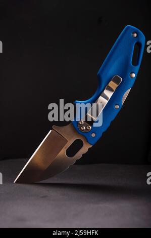 Folding pocket knife with blue plastic handle. Knife with a clip for carrying. Knife on a black background. Stock Photo