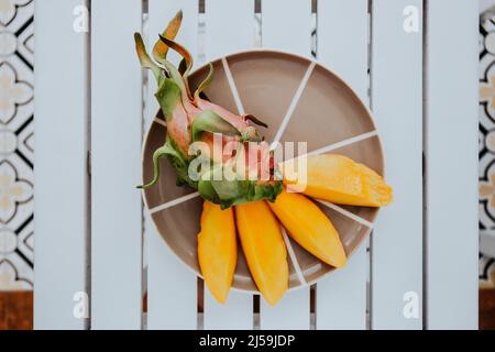 Fresh mango and dragon fruit on plate. Fresh tropical exotic fruits. Concept of a raw food diet, vegetarianism and replenishment of vitamins with Stock Photo