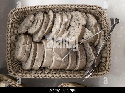 Delicious slices of black bread on the table in a wicker basket. Top view, close-up. Stock Photo