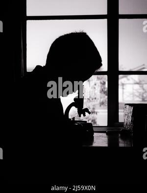1970s ANONYMOUS SILHOUETTE BOY LOOKING THROUGH MICROSCOPE AT HOME - j12737 HAR001 HARS OLD FASHIONED Stock Photo