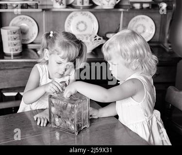 1970s TWO LITTLE BLOND GIRLS SISTERS PUTTING MONEY SAVING COINS IN THEIR PIGGY BANK - j12823 HAR001 HARS JOY LIFESTYLE SATISFACTION CELEBRATION FEMALES CURRENCY HOME LIFE UNITED STATES COPY SPACE HALF-LENGTH INSPIRATION SIBLINGS SISTERS B&W GOALS HAPPINESS STRATEGY CHOICE EXCITEMENT QUARTERS PRIDE OPPORTUNITY SIBLING NICKELS CONCEPTUAL DIMES STYLISH HALF DOLLARS COOPERATION GROWTH JUVENILES PENNIES TOGETHERNESS BLACK AND WHITE CAUCASIAN ETHNICITY HAR001 OLD FASHIONED Stock Photo