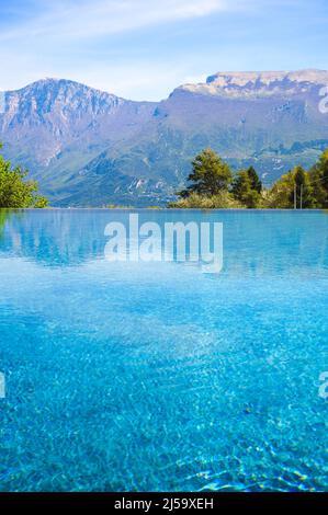 Outdoor infinity swimming pool at luxury hotel with mountains, Garda lake, Italy Stock Photo
