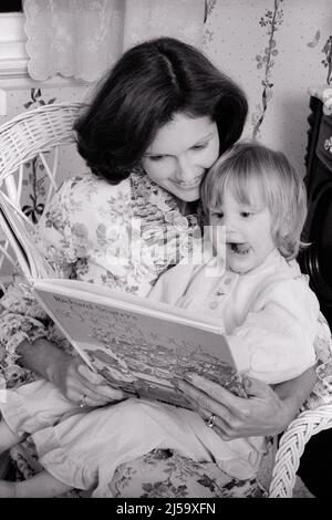 1970s SMILING WOMAN MOTHER READING BOOK TO ENGROSSED GIRL TODDLER DAUGHTER SITTING ON HER LAP IN WICKER CHAIR - j13501 HAR001 HARS HER MOTHERS SURPRISED EXPRESSION OLD TIME SURPRISE NOSTALGIA READ OLD FASHION 1 JUVENILE FACIAL COMMUNICATION BEDTIME FAMILIES JOY LIFESTYLE FEMALES HOME LIFE FRIENDSHIP HALF-LENGTH LADIES DAUGHTERS PERSONS WICKER EXPRESSIONS B&W LAP HAPPINESS HEAD AND SHOULDERS RECREATION IN ON TO STORIES HIGH TECH CONNECTION ENGROSSED CONCEPTUAL GROWTH JUVENILES MOMS BLACK AND WHITE CAUCASIAN ETHNICITY HAR001 OLD FASHIONED Stock Photo