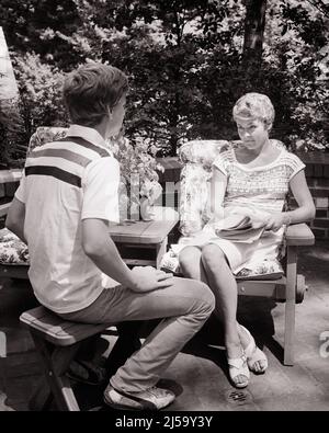 1970s WOMAN MOTHER SITTING ON OUTDOOR PATIO HOLDING A NEWSPAPER HAVING A SERIOUS CONVERSATION WITH HER TEENAGE BOY SON - j14211 HAR001 HARS MOTHERS OLD TIME FUTURE NOSTALGIA INDUSTRY OLD FASHION CONVERSATION 1 JUVENILE COMMUNICATION STRONG FEMALES PATIO HEALTHINESS HOME LIFE COPY SPACE FULL-LENGTH LADIES PERSONS THOUGHTFUL CARING MALES TEENAGE BOY B&W HAPPINESS WELLNESS CONSULTING PRIDE AUTHORITY CONNECTION CONCEPTUAL SUPPORT TEENAGED SINCERE PERSONAL ATTACHMENT SOLEMN AFFECTION EMOTION FOCUSED GROWTH INTENSE JUVENILES MID-ADULT MID-ADULT WOMAN MOMS TOGETHERNESS BLACK AND WHITE CAREFUL