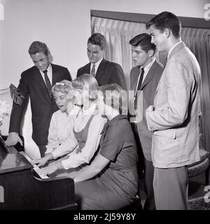 1950s GROUP OF SEVEN TEENAGERS BOYS AND GIRLS AROUND A PIANO PLAYING AND SINGING - j189 HAR001 HARS SINGERS JOY LIFESTYLE SOUND SATISFACTION MUSICIAN CELEBRATION FEMALES HOUSES COPY SPACE FRIENDSHIP HALF-LENGTH PERSONS INSPIRATION RESIDENTIAL MALES TEENAGE GIRL TEENAGE BOY BUILDINGS ENTERTAINMENT B&W SCHOOLS SUIT AND TIE HAPPINESS AND EXCITEMENT RECREATION SONG VOCAL PRIDE OPPORTUNITY ENTERTAINER HIGH SCHOOL HOMES MUSICAL INSTRUMENT HIGH SCHOOLS CONNECTION VOCALIZE CONCEPTUAL VOCALS 7 RESIDENCE SONGS STYLISH TEENAGED CHORAL COOPERATION GROWTH JUVENILES TOGETHERNESS BLACK AND WHITE Stock Photo