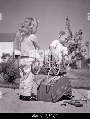 1940s 1950s LITTLE BOY REPAIRING TOY BABY CARRIAGE AS THE OWNER A LITTLE BLONDE GIRL WAITS ON SUBURBAN SIDEWALK  - j3726 HAR001 HARS JOY LIFESTYLE FEMALES BROTHERS HOME LIFE COPY SPACE FRIENDSHIP FULL-LENGTH GROUND PERSONS INSPIRATION CARING MALES SIBLINGS CONFIDENCE FIXING SISTERS B&W GOALS CARRIAGE HAPPINESS WATCHES OWNER AND LOW ANGLE PRIDE A AS ON THE SIBLING USING REPAIRING CONNECTION LOTS CONCEPTUAL SUPPORT T-SHIRT WAITS JUVENILES PRECISION TOGETHERNESS BABY CARRIAGE BLACK AND WHITE CAUCASIAN ETHNICITY HAR001 OLD FASHIONED Stock Photo