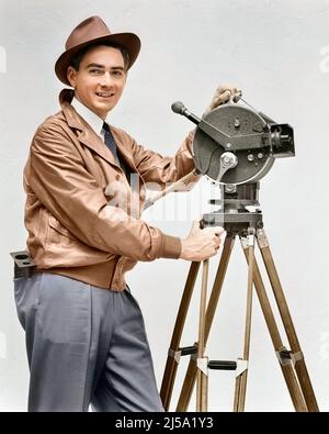 1930s SMILING MAN CINEMATOGRAPHER OPERATING AKELEY HAND CRANK MOVIE CAMERA LOOKING AT CAMERA WEARING LEATHER JACKET FEDORA HAT - u153c HAR001 HARS COMMUNICATION CAREER TECHNOLOGY INFORMATION PLEASED JOY LIFESTYLE JOBS STUDIO SHOT MOTION FILMING COPY SPACE HALF-LENGTH PERSONS INSPIRATION MALES CAMERAMAN PROFESSION CONFIDENCE PORTABLE TRIPOD EYE CONTACT CRANK FEDORA SKILL OCCUPATION HAPPINESS SKILLS OPERATING CHEERFUL ADVENTURE STRATEGY CAREERS CHOICE KNOWLEDGE DIRECTION LABOR PRIDE ON AUTHORITY EMPLOYMENT OCCUPATIONS SMILES CONNECTION CONCEPTUAL IMAGINATION JOYFUL STYLISH EMPLOYEE Stock Photo