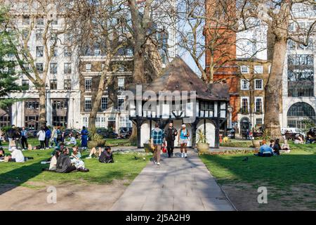 People enjoying the warmer weather arriving in the UK, Soho Square, London, UK Stock Photo